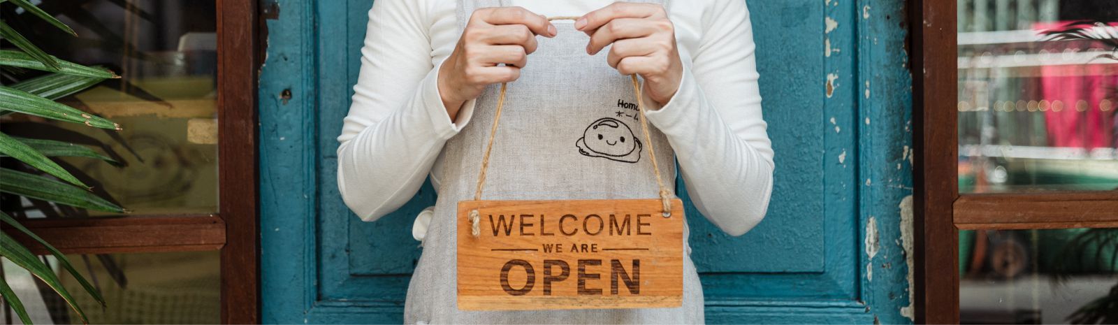 a person holding a welcome we are open sign
