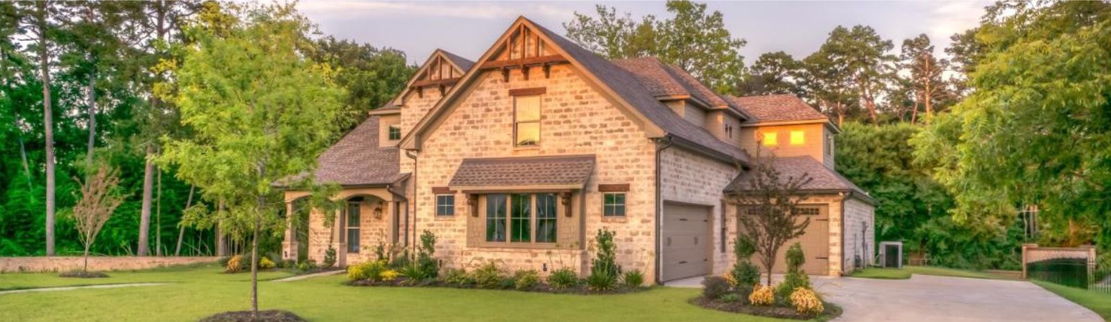 a brick house surrounded by green trees